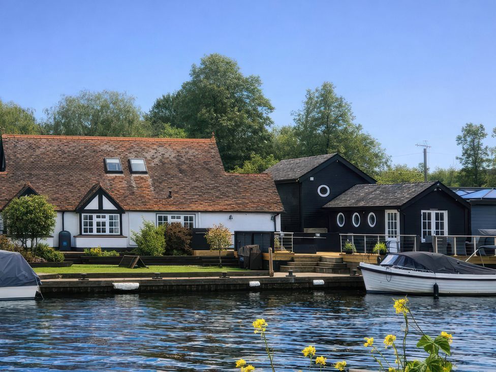 A house with a dock and boat by the water at Island Cottage Rod eyot Henley-On-Thames