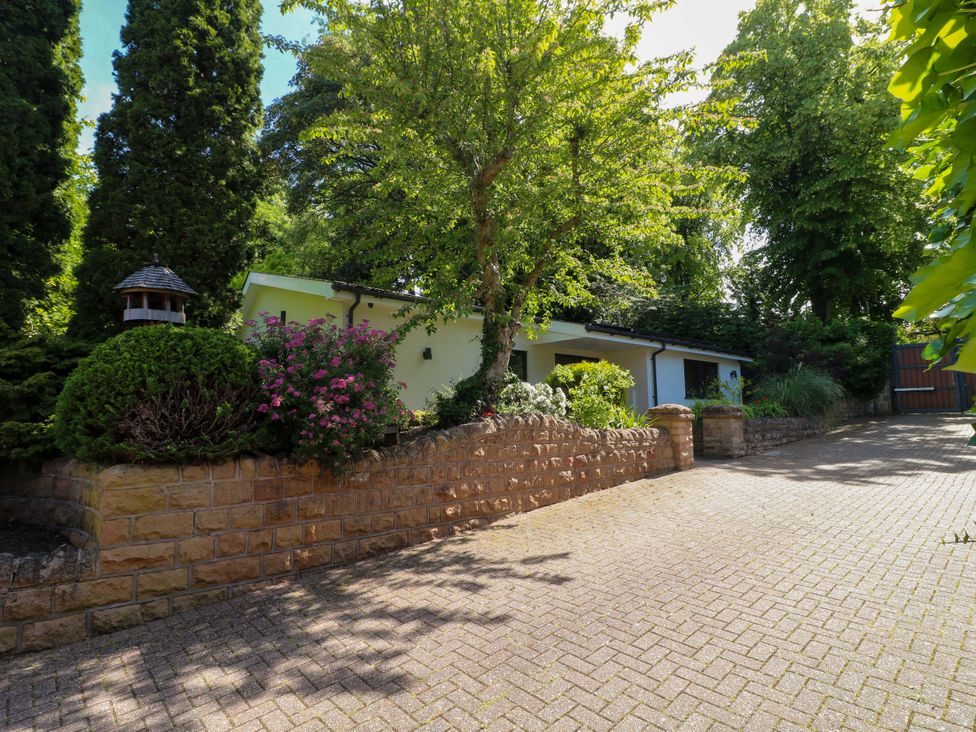 An outdoor view of a house with trees and flowers at Elmcroft in Nottingham