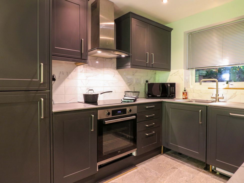 A kitchen with cabinets, sink, microwave and oven at Elmcroft in Nottingham