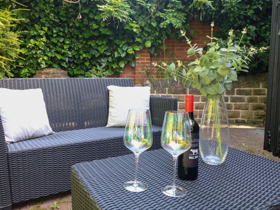 A garden seating area with a table, wine glasses, and a bottle at Elmcroft in Nottingham