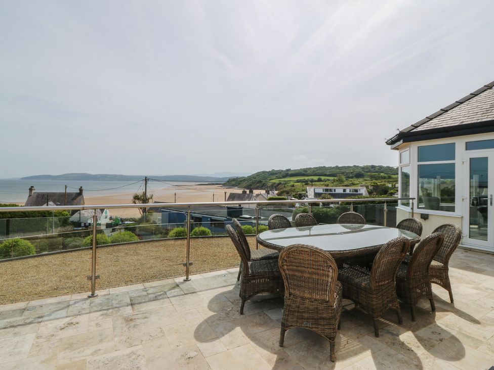 An outdoor dining area with a table and chairs overlooking the sea at Hillside