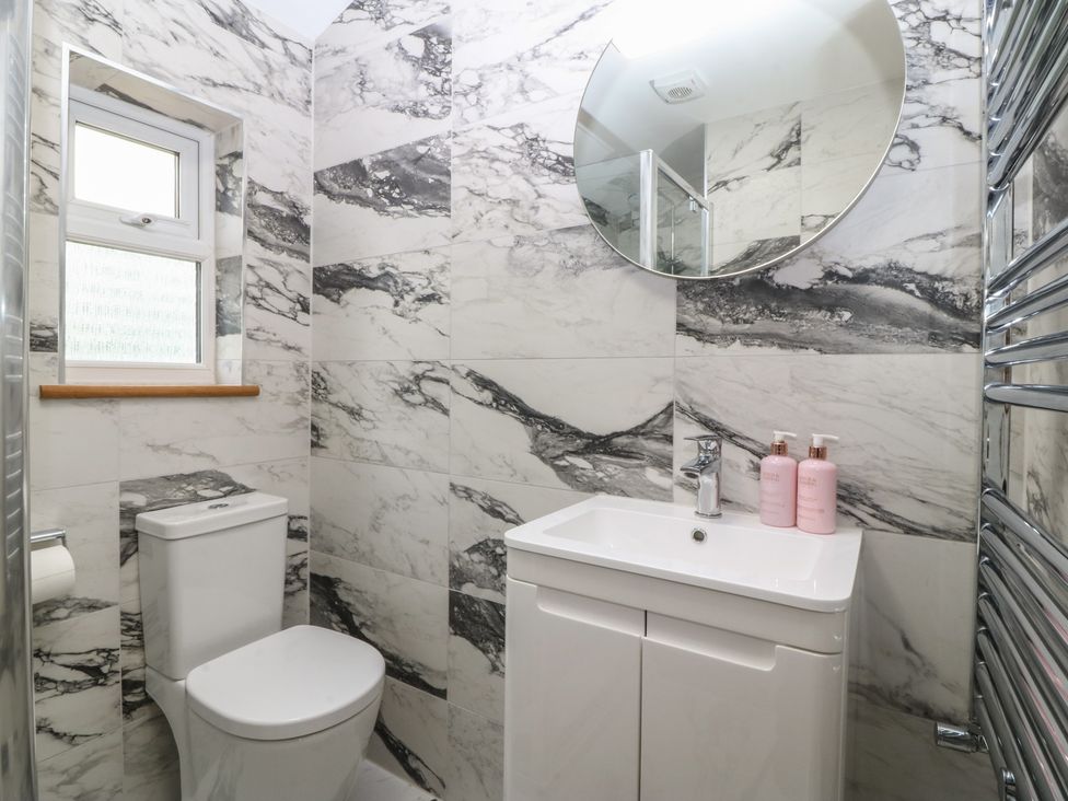A bathroom with a sink, toilet, mirror, and towel radiator at Hillside