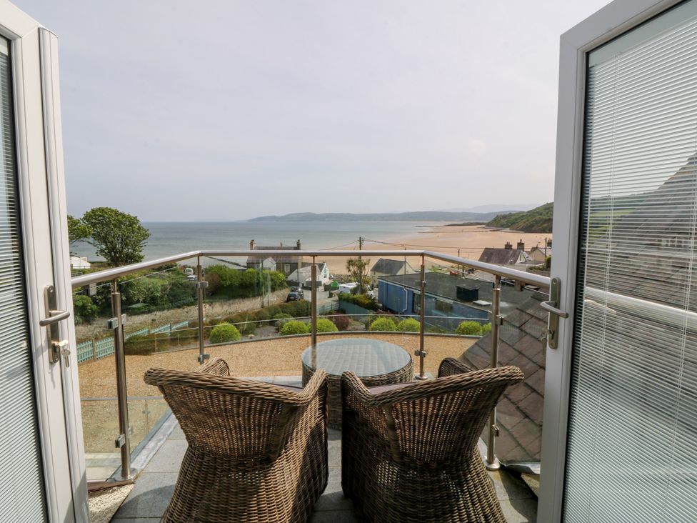 A balcony with wicker chairs and a table overlooking the sea at Hillside
