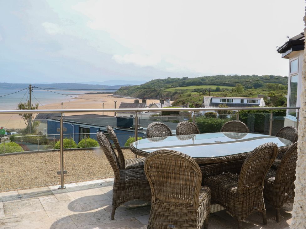 An outdoor dining area with a table and chairs overlooking a beach and hills at Hillside