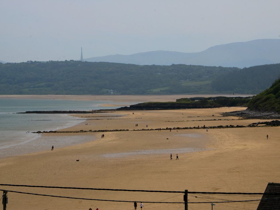 A beach with people walking and hills in the background at Hillside