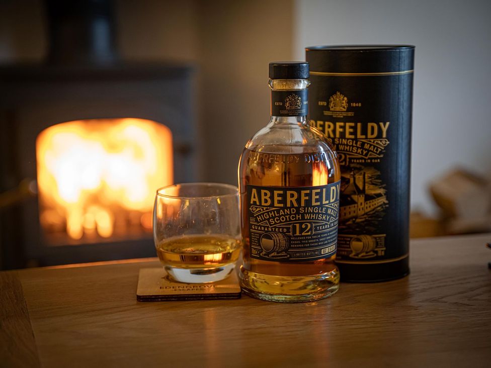A whiskey bottle and glass near a fireplace at Edengrove in Aberfeldy