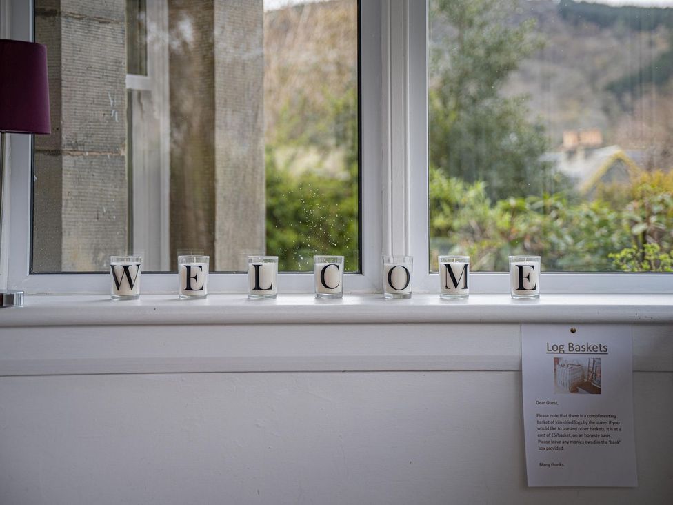 A window with candles spelling welcome and a log basket sign at Edengrove in Aberfeldy