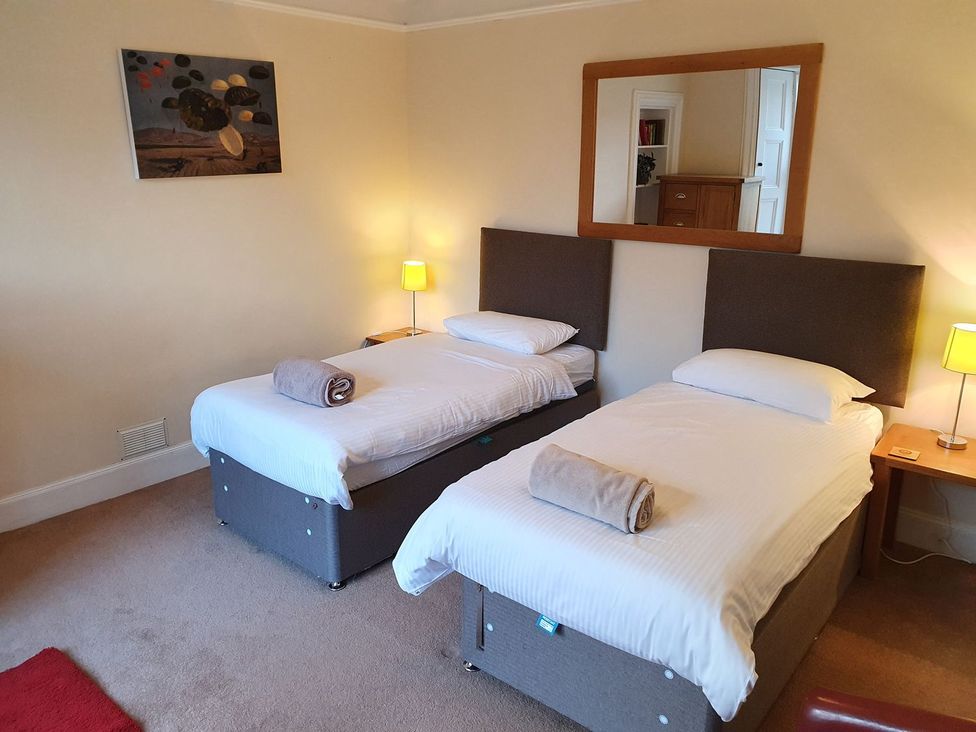 A bedroom with twin beds and a mirror at Edengrove Aberfeldy