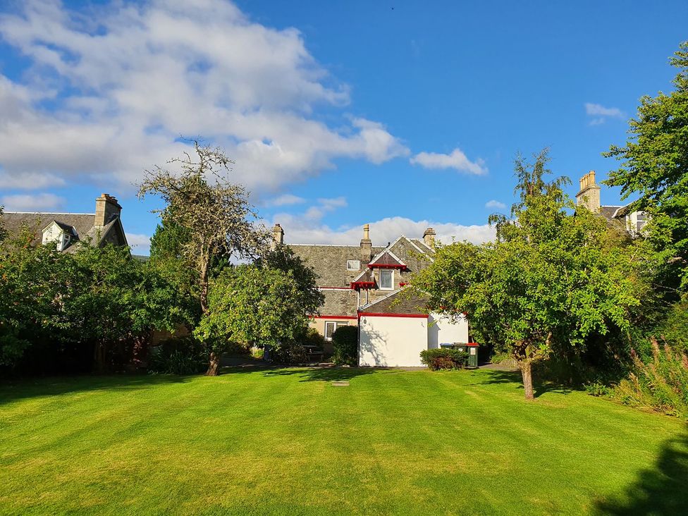 A garden with a house and trees at Edengrove in Aberfeldy