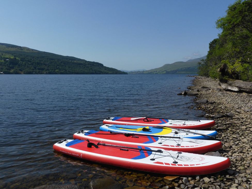 Paddleboards on the shore of a lake with trees in the background at Edengrove, Aberfeldy