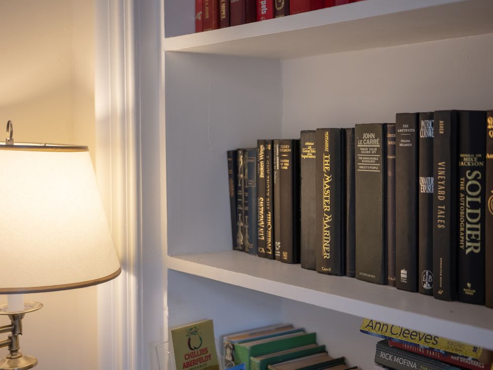 A living room with a lamp and books on a shelf at Edengrove Aberfeldy