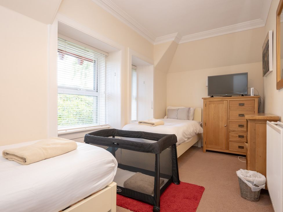 A bedroom with a bed, crib, and television at Edengrove in Aberfeldy