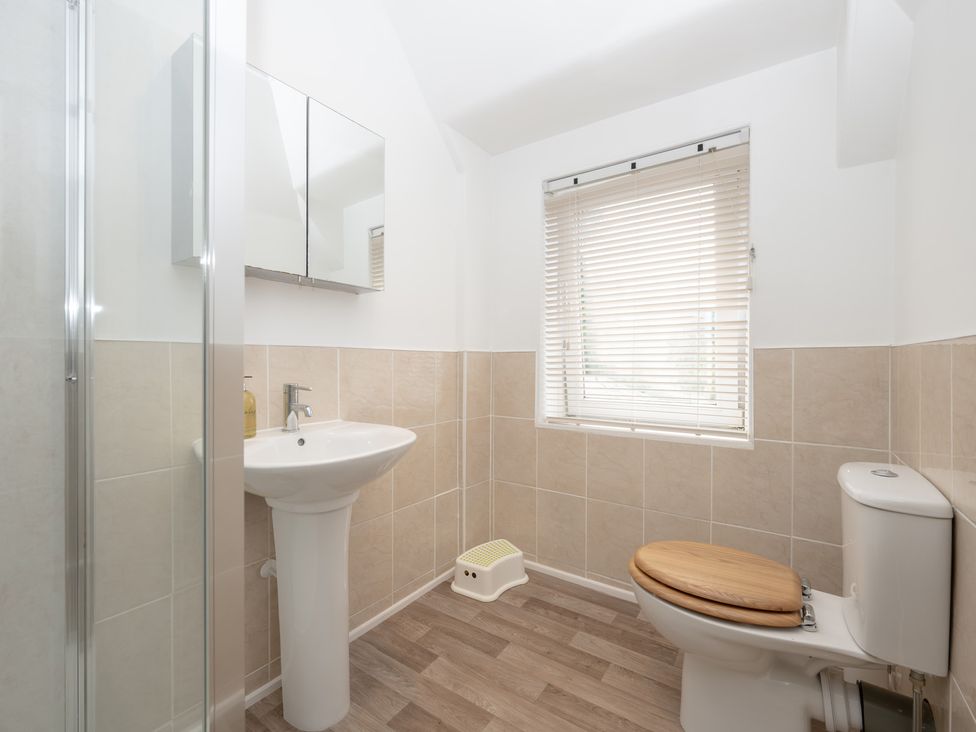 A bathroom with a toilet, sink, mirror and shower at Edengrove in Aberfeldy