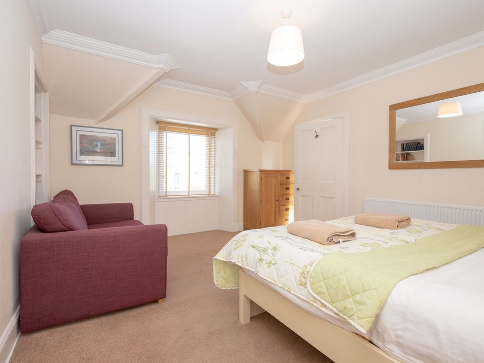 A bedroom with a bed, sofa, and window at Edengrove in Aberfeldy