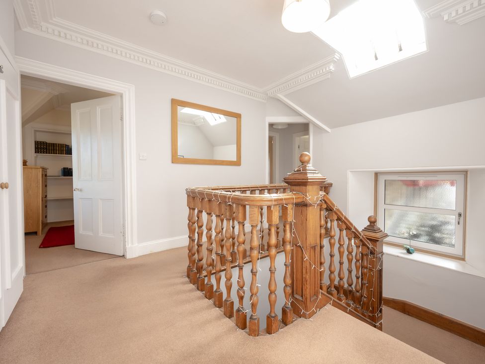 A hallway with wooden stairs and a mirror at Edengrove in Aberfeldy
