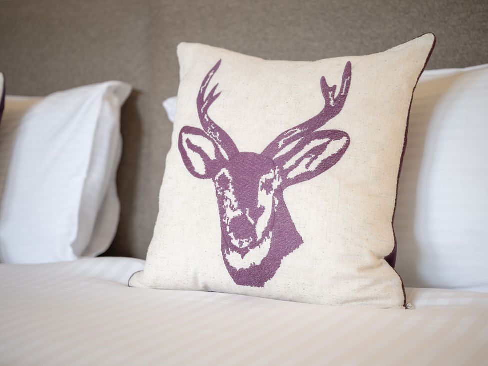 A pillow with a deer design on a bed at Edengrove Aberfeldy