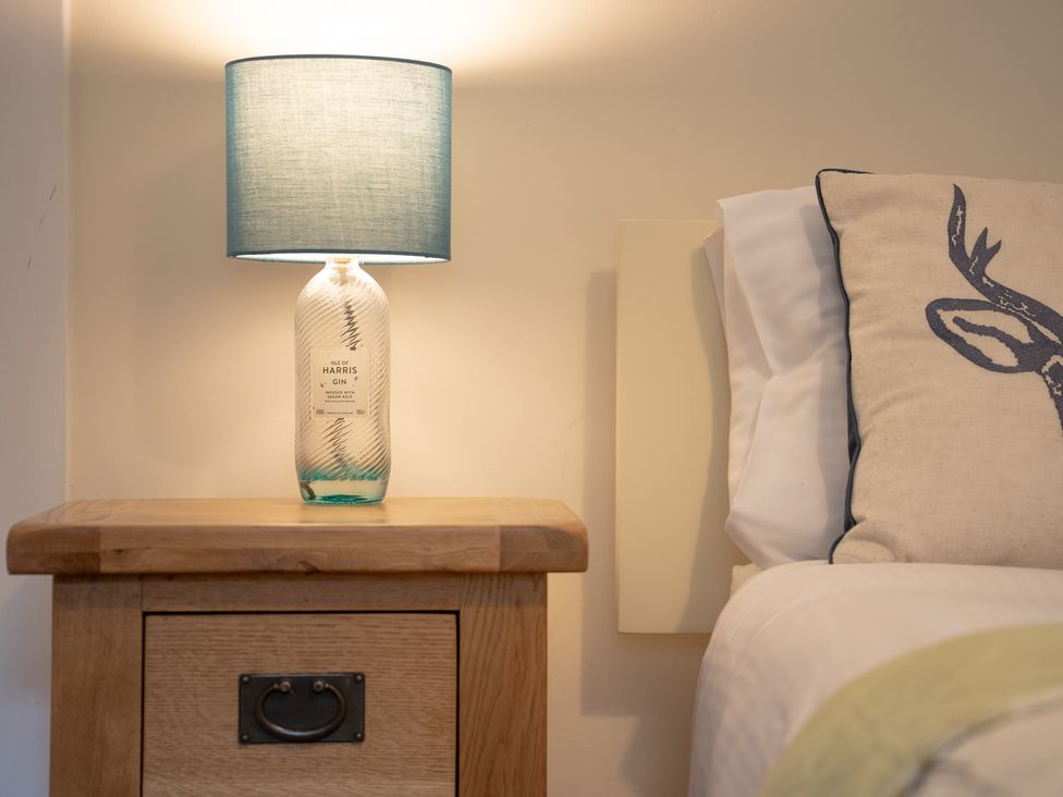 A bedside table with a lamp and cushion at Edengrove in Aberfeldy