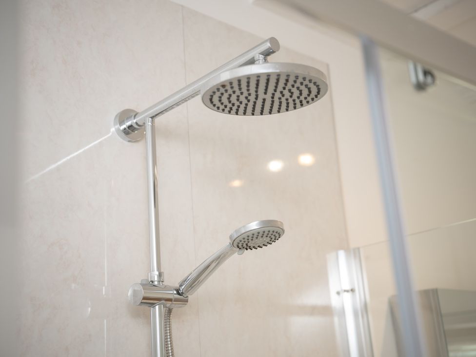 A shower with overhead and handheld showerheads at Edengrove in Aberfeldy