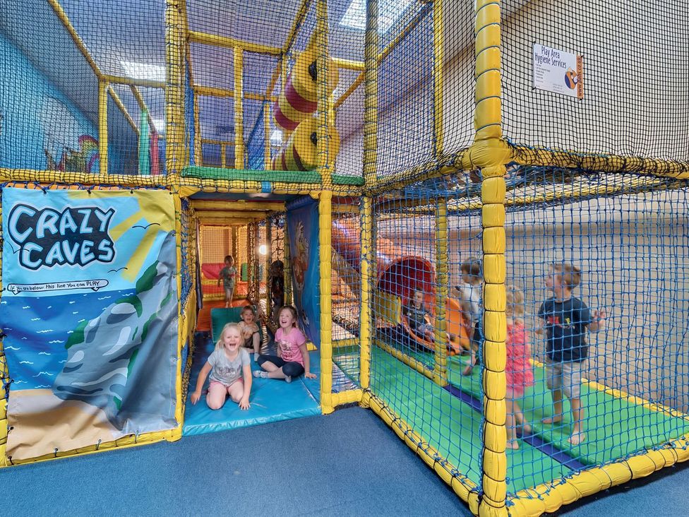 A play area with a netted structure and children playing at Tide’s Reach - Hayling Island