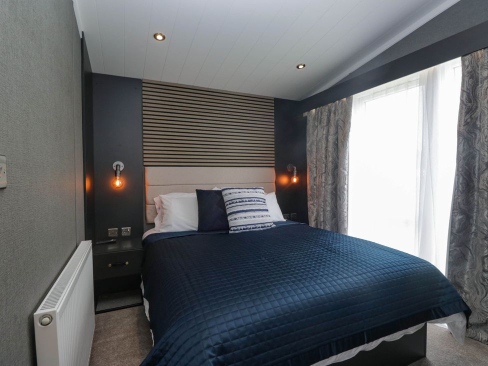 A bedroom with a bed and curtains at Heron in Haverigg