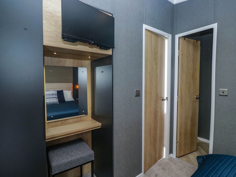 A bedroom with a television and mirror at Heron in Haverigg