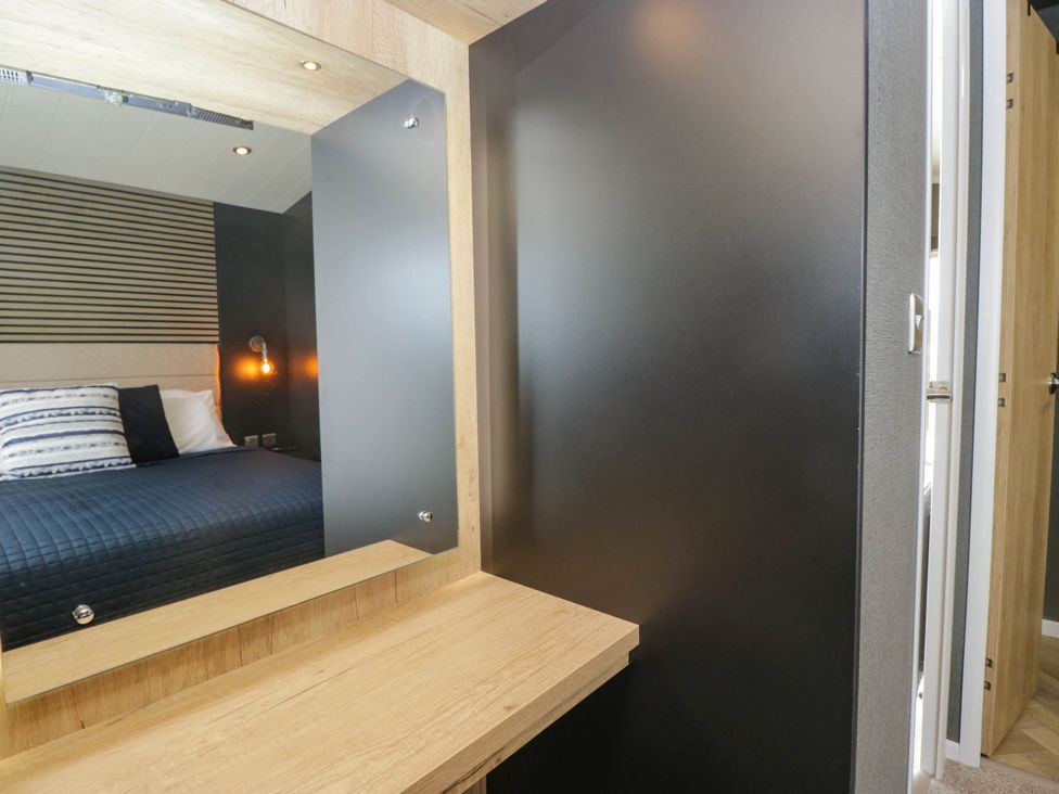 A bedroom with a bed and a mirror at Heron in Haverigg