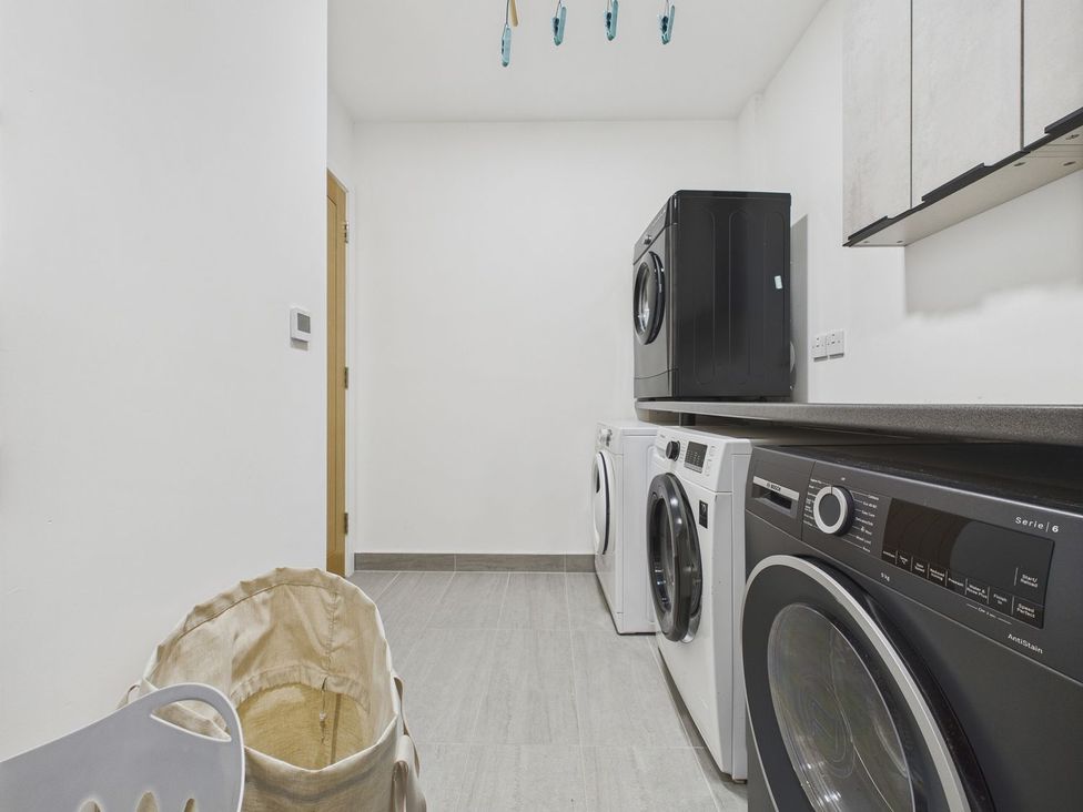 A laundry room with washing machines and a clothes basket at Oakwood House in Tansley near Matlock