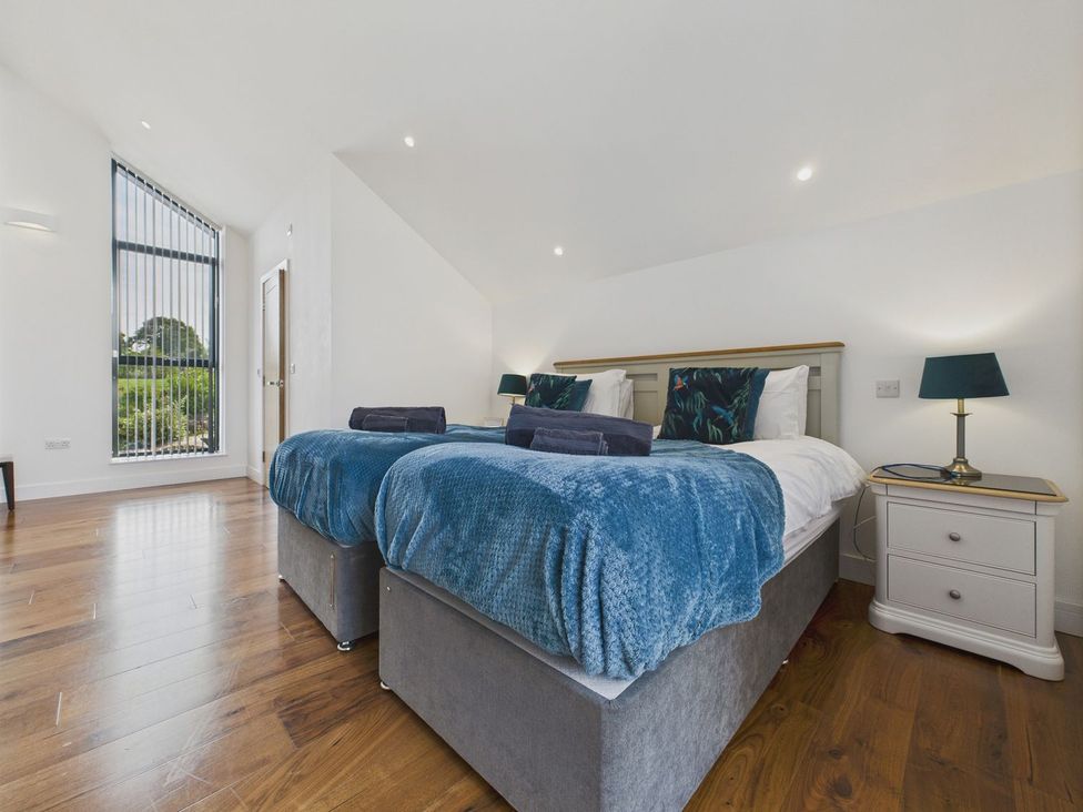 A bedroom with two beds and a nightstand at Oakwood House in Tansley near Matlock