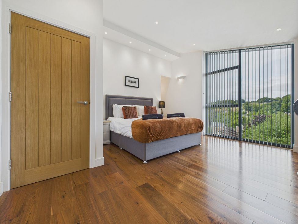 A bedroom with a bed, nightstand, and a window at Oakwood House in Tansley near Matlock