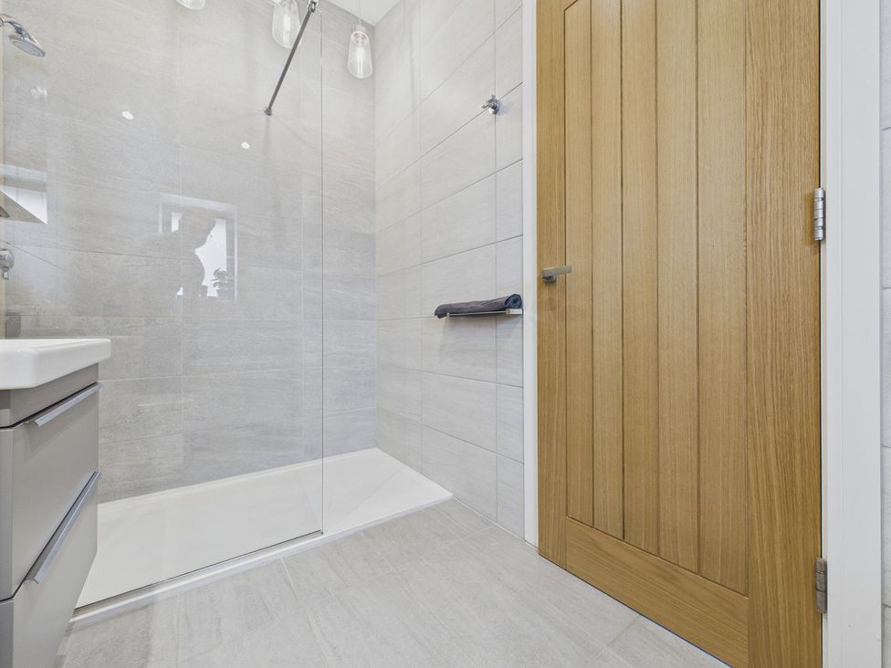 A bathroom with a shower and a wooden door at Oakwood House Tansley near Matlock
