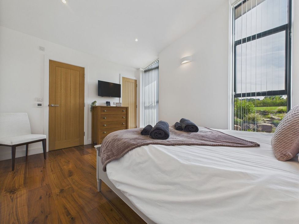 A bedroom with a bed, towels, chair and television at Oakwood House in Tansley near Matlock