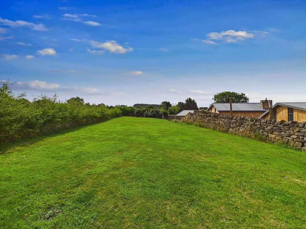 An outdoor area with grass and a stone wall at Oakwood House in Tansley near Matlock