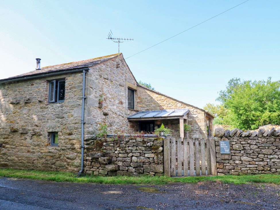 A stone house with a gate and trees at The Brew House in Penrith