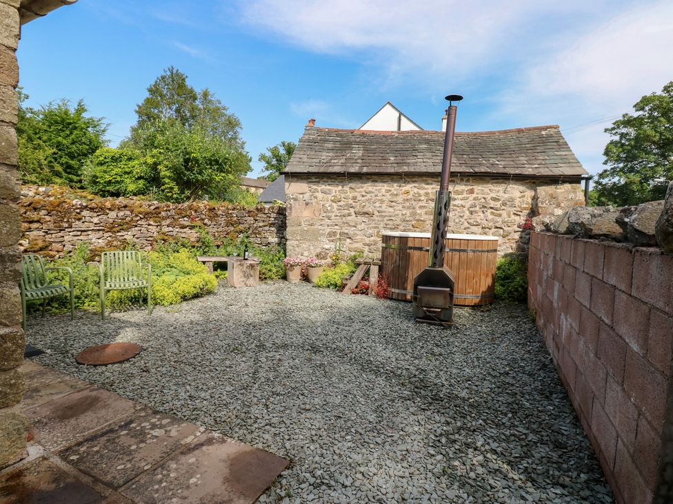 A garden with gravel, chairs and a wooden hot tub at The Brew House in Penrith