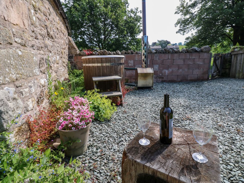 An outdoor area with a wine bottle and glasses on a wooden table at The Brew House in Penrith