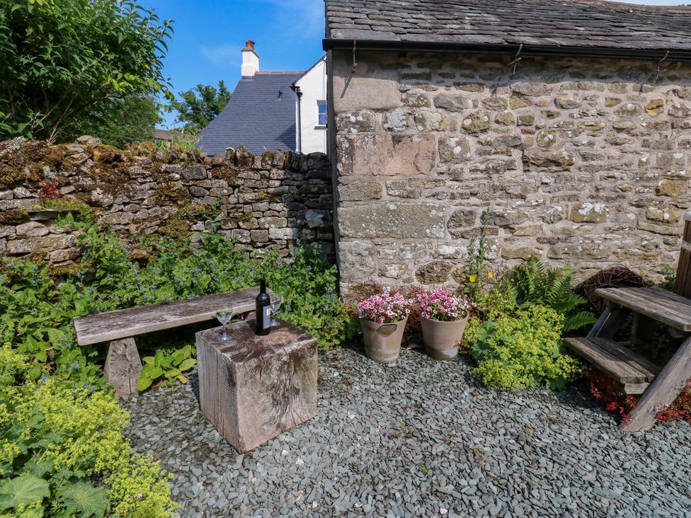 A garden with a stone wall, wooden furniture, and plants at The Brew House in Penrith
