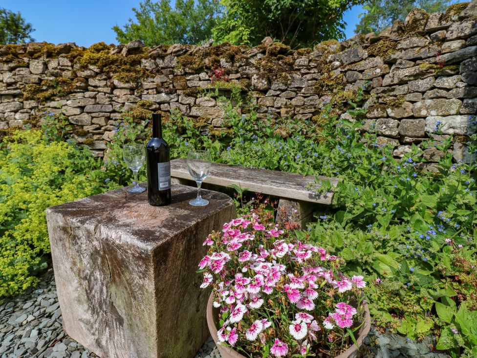A garden with a wine bottle and glasses on a wooden bench at The Brew House in Penrith