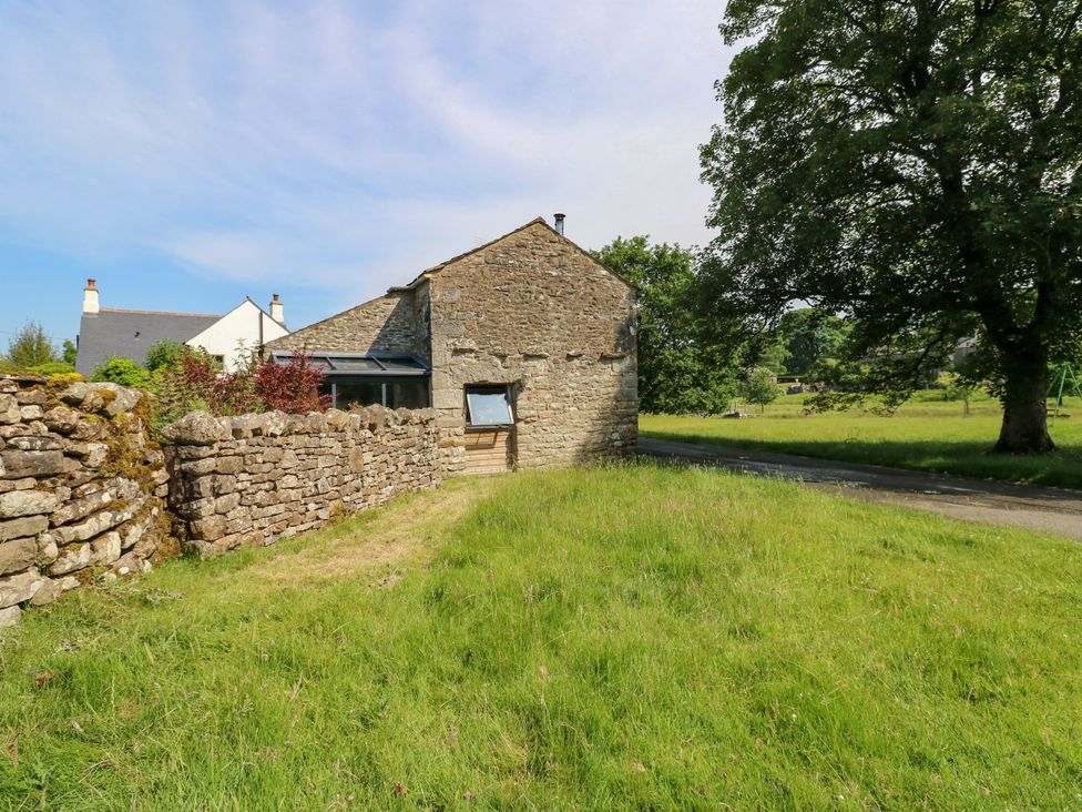 An outdoor view of a house with a stone wall and grass at The Brew House in Penrith