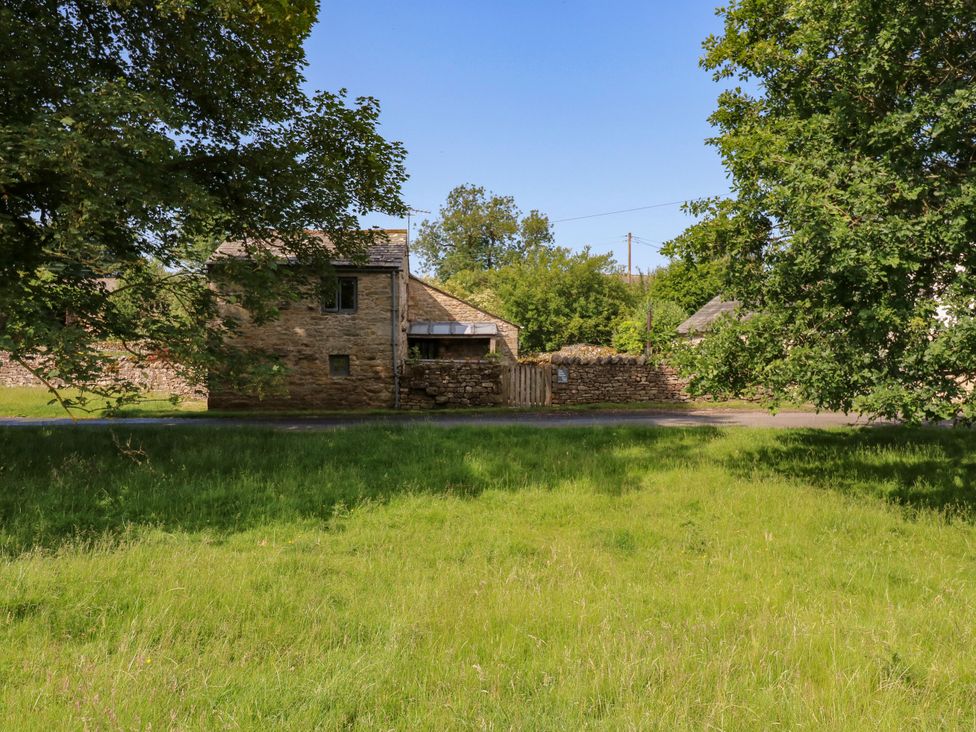 A house with stone walls and trees in a field at The Brew House in Penrith