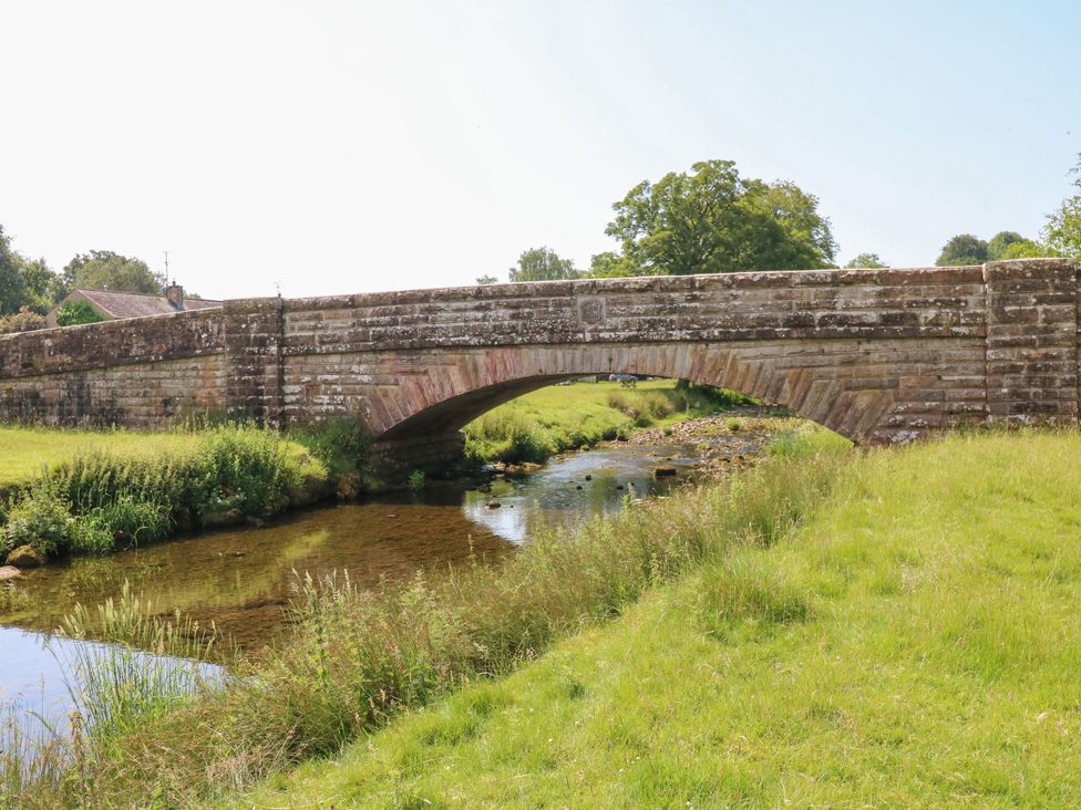 A bridge over a stream with grassy banks at The Brew House in Penrith