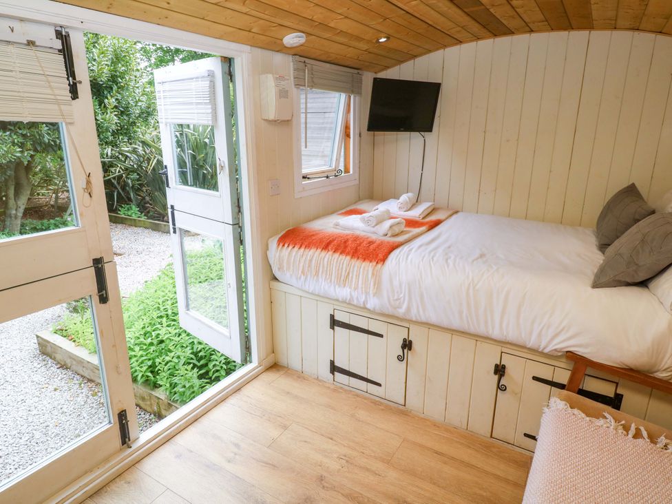 A bedroom with a bed and open door at Shepherds Hut in Truro