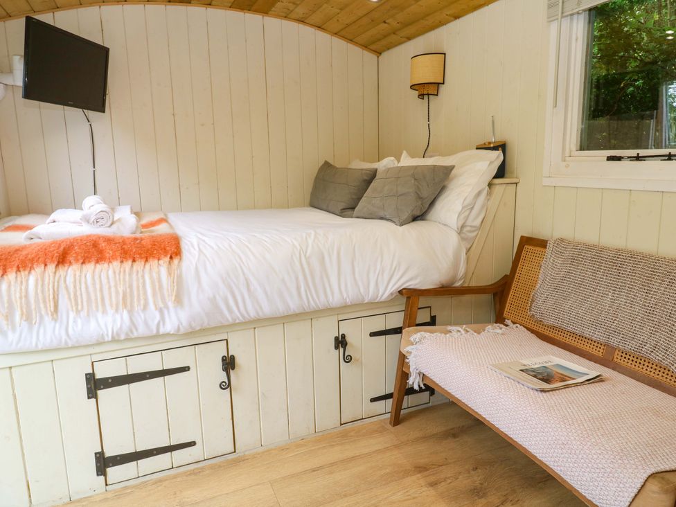 A bedroom with a bed and tv at Shepherds Hut in Truro