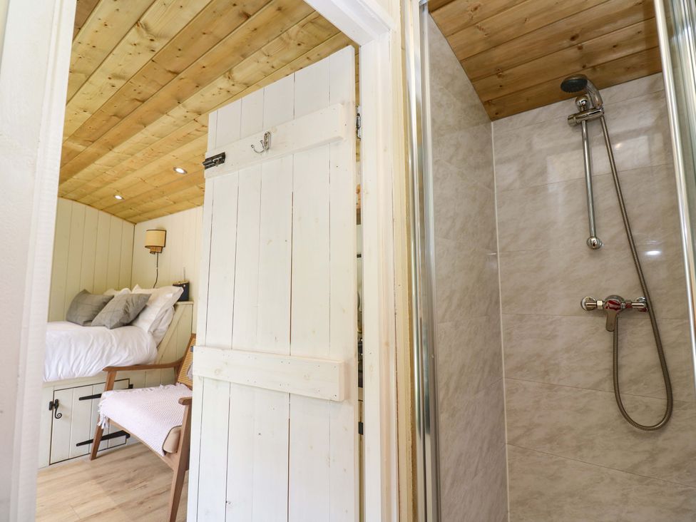 A bedroom with a bed and a shower area at Shepherds Hut in Truro