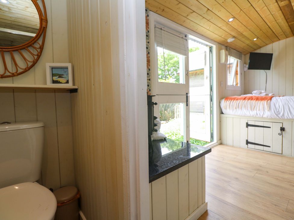A bathroom with toilet and mirror at Shepherds Hut in Truro