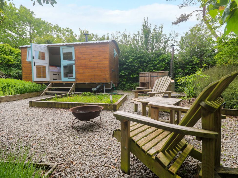 A garden with a wooden hut and chairs at Shepherds Hut in Truro