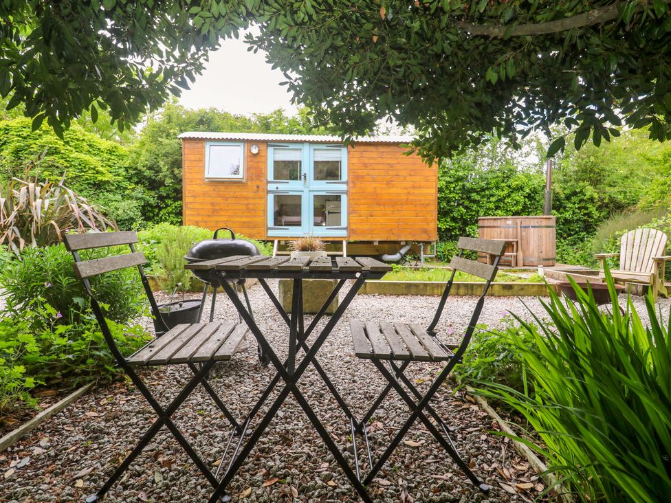 A garden with a wooden hut and seating area at Shepherds Hut in Truro