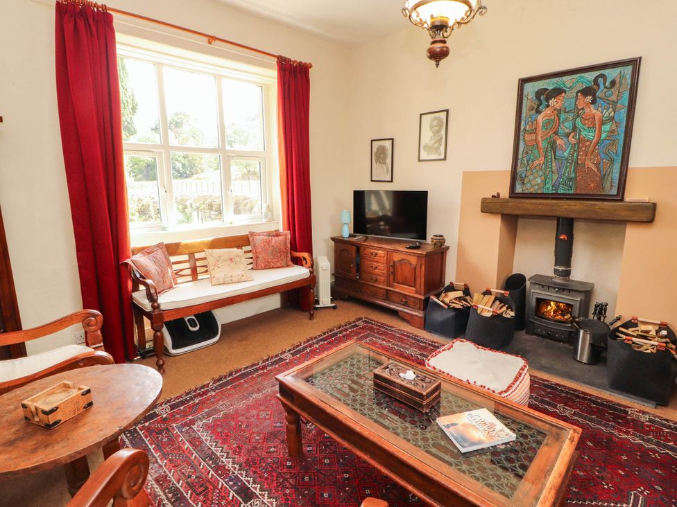A living room with a sofa, tv, and fireplace at The School House in Penrith