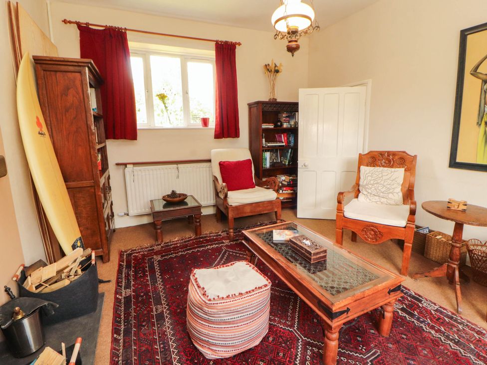 A living room with a surfboard and books on a shelf at The School House in Penrith