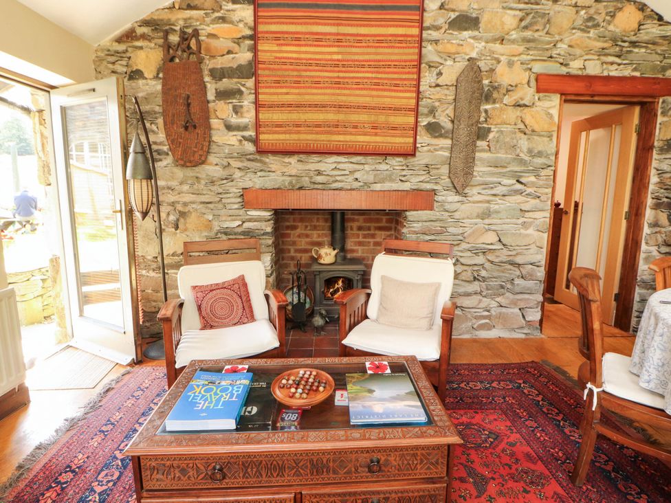 A living room with a fireplace and wooden chairs at The School House in Penrith