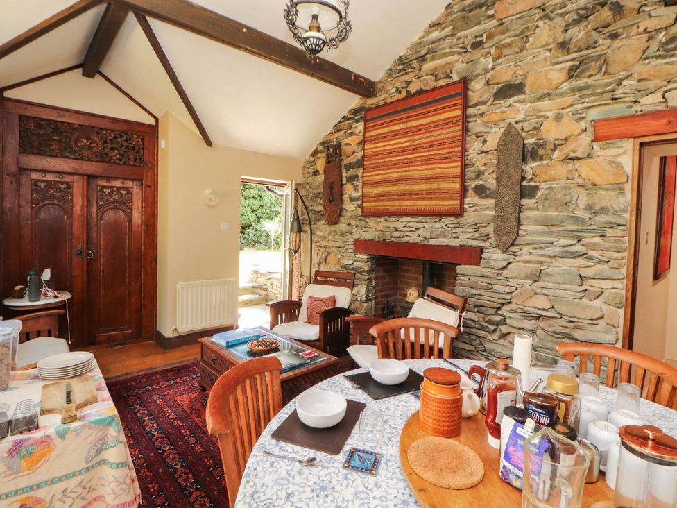 A dining room with a stone wall and wooden furniture at The School House in Penrith